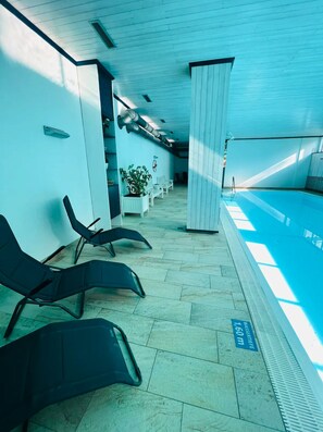 A poolside area with lounge chairs, a potted plant, and a sign indicating the pool depth.