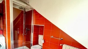 A bathroom with red tiles, a shower, a toilet, a bidet, and a radiator. - Casa Breton (Turin)