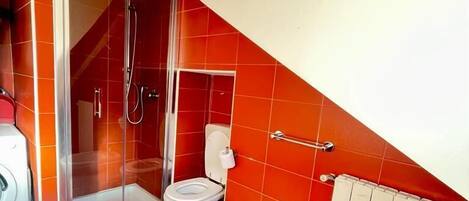 Un baño con baldosas rojas, ducha, inodoro, bidé y radiador.