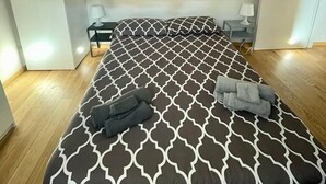 A bedroom with a patterned bedspread, a bedside table with a lamp, a wardrobe, and a small desk with a chair. - Casa Breton (Turin)