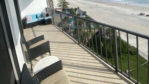 A balcony with wicker furniture overlooking a beach. - Fantastic and completely updated direct ocean front condo at the Caribbean (Daytona Beach Shores)