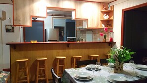 Cocina compacta con taburetes de madera, una mesa de comedor para cuatro personas y un refrigerador.