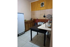 A compact kitchen with a refrigerator, stove, and wooden cabinets.