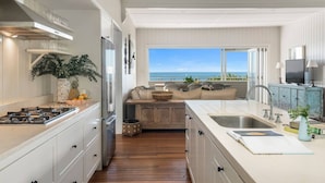 Una cocina moderna con una isla grande, suelo de madera y vistas al océano.