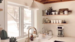 A kitchen with a wooden ceiling, white countertops, a sink, and a window. - Maine lake front ski getaway! (Greenwood)