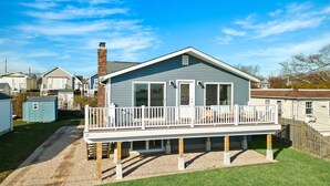 Een huis met één verdieping, voorzien van een overdekte veranda, schoorsteen en een klein terras.