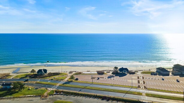 Een kustweg met een parkeerplaats en toegang tot het strand.