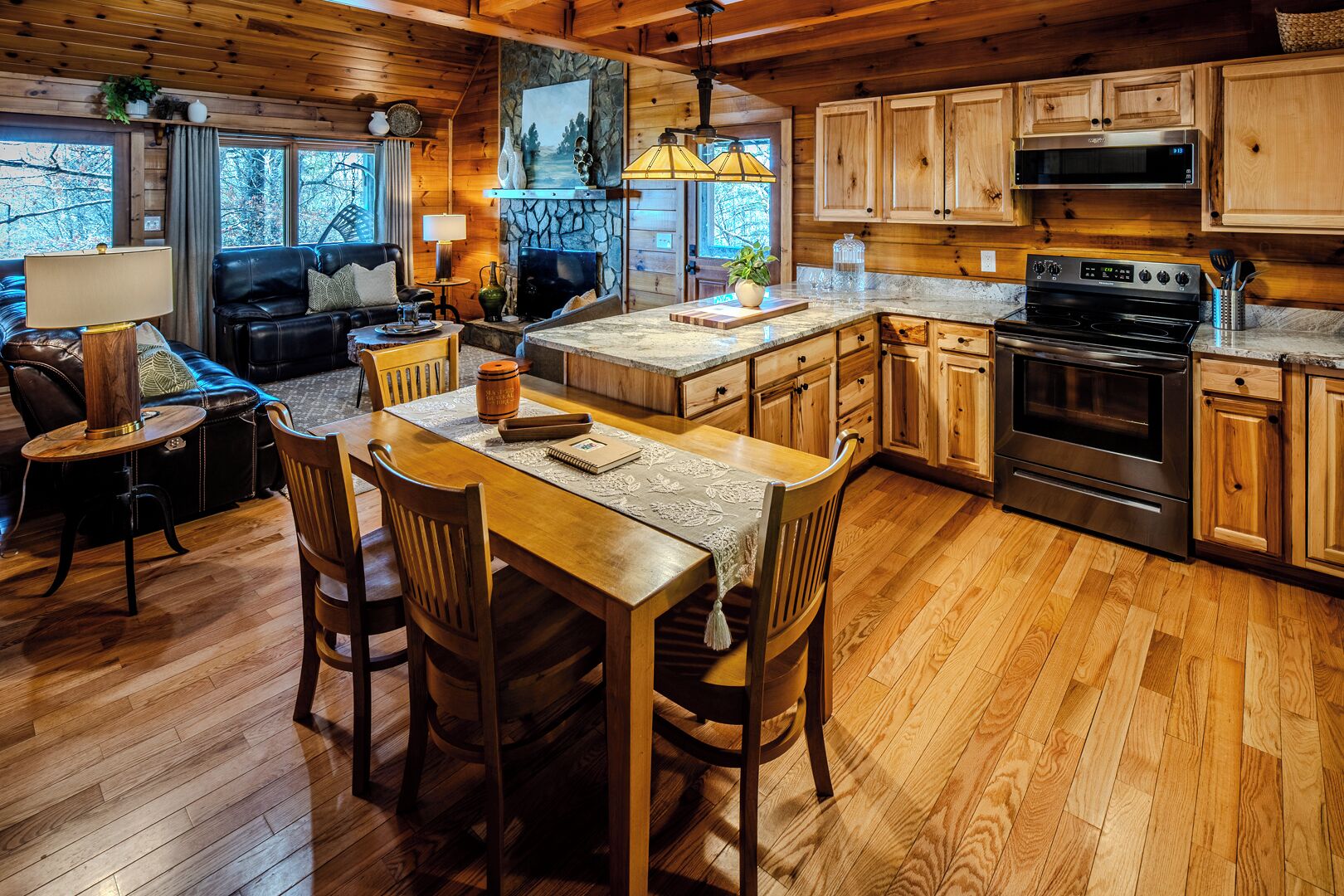 A cozy cabin-style kitchen with wooden cabinets, a stone fireplace, and a dining area with a table and chairs.