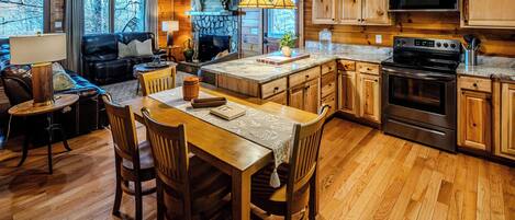 A cozy cabin-style kitchen with wooden cabinets, a stone fireplace, and a dining area with a table and chairs.