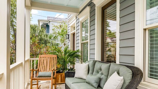 A covered porch with a wicker sofa, a rocking chair, and potted plants. - Hot Tub • Porches • Parking • Walk to King St! (Charleston)