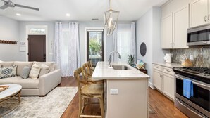 A modern kitchen with a central island, white cabinetry, and stainless steel appliances. - Hot Tub • Porches • Parking • Walk to King St! (Charleston)