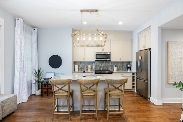 A modern kitchen with a central island, stainless steel appliances, and a pendant light. - Peaceful Porch • Parking • Walk to King St! (Charleston)