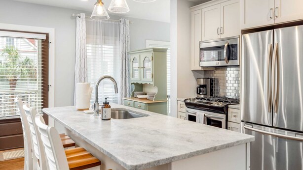 A modern kitchen with a marble island, stainless steel appliances, and white cabinetry.