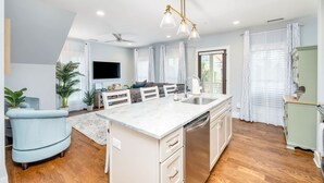 A modern kitchen with a central island, white cabinetry, and a ceiling fan.