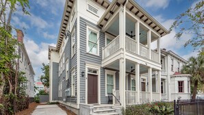 A two-story house with a front porch, a balcony, and a small garden area.