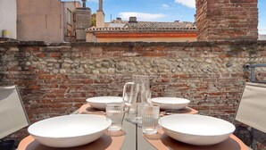 Un espacio de comedor al aire libre con paredes de piedra, una chimenea de ladrillo y cielo despejado.