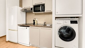 Cocina compacta equipada con refrigerador, microondas, lavavajillas y lavadora.