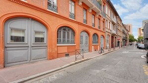 Una calle con edificios que tienen grandes ventanales y puertas de arco, una acera, y una bicicleta estacionada al lado.