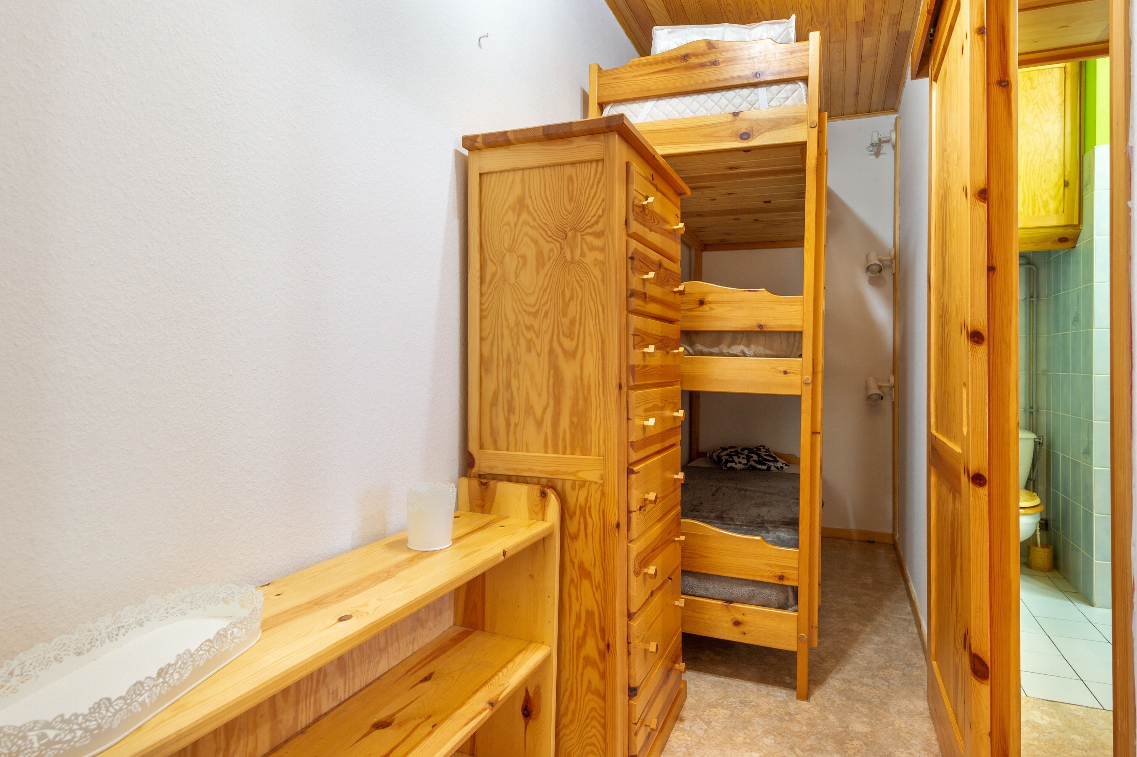 A wooden bunk bed with drawers, a bedside table, and a small shelf.