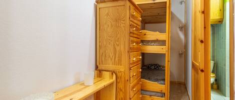 A wooden bunk bed with drawers, a bedside table, and a small shelf.