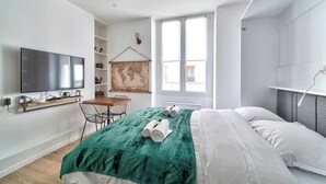 A modern bedroom with a bed, a TV, a desk, and a window. - Magnifique studio - Le Marais (Paris)