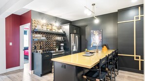 A modern kitchen with a central island, black cabinetry, and a wine rack.
