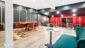 A modern interior with a dining area, a red curtain backdrop, and a green sofa.