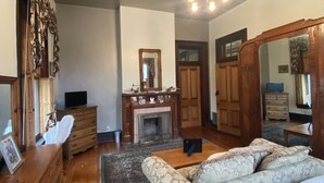 Een ruime slaapkamer met een groot bed, een houten dressoir, een kaptafel en een open haard.
