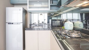A modern kitchen with a built-in microwave, stainless steel appliances, and a large island with a sink. - Elegant And Spacious 3Br At Ciputra International Apartment (Jakarta)