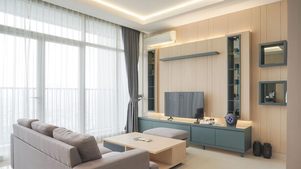 A modern living room with a sofa, coffee table, TV, and built-in shelving. - Elegant And Spacious 3Br At Ciputra International Apartment (Jakarta)