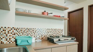 Una cocina con pileta, encimera, estufa y repisas superiores.
