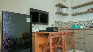 Una cocina compacta con televisor integrado, armarios de madera y salpicadero de azulejos.