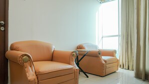 Una habitación con dos sofás de cuero naranja, una mesita y un ventanal con cortinas.