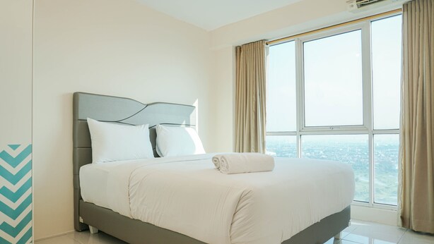 Una habitación de hotel moderna con una cama grande, vistas a la ciudad y un ventanal con cortinas.