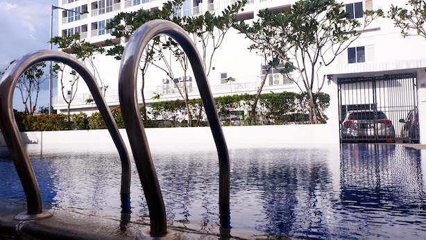 A swimming pool with metal railings, a white building, and a car parked in a gated area. - Cozy Stay And Homey Studio At Tifolia Apartment (Jakarta)
