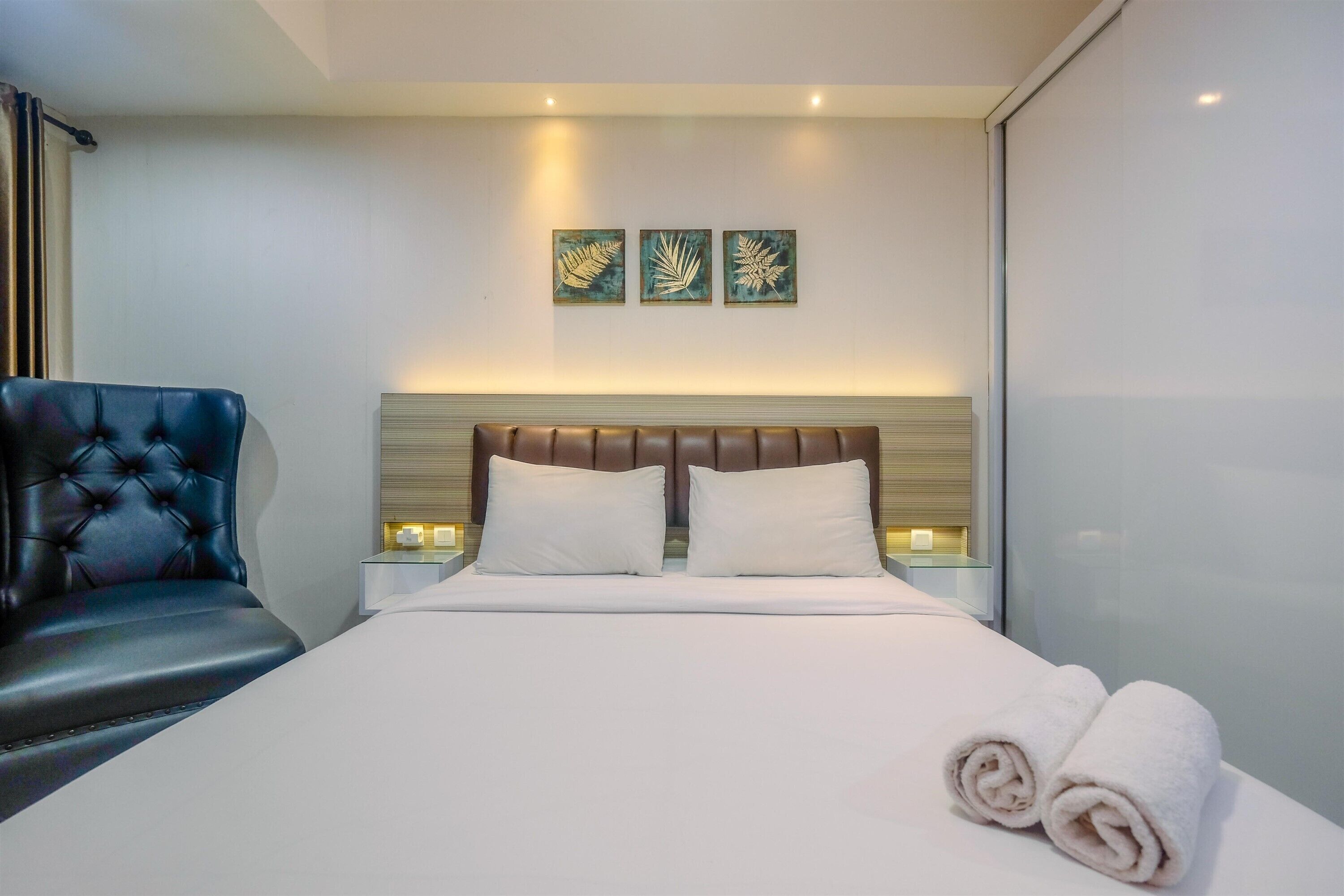 Et moderne hotelværelse med en stor seng, en læderlænestol og tre billeder hængt på væggen.