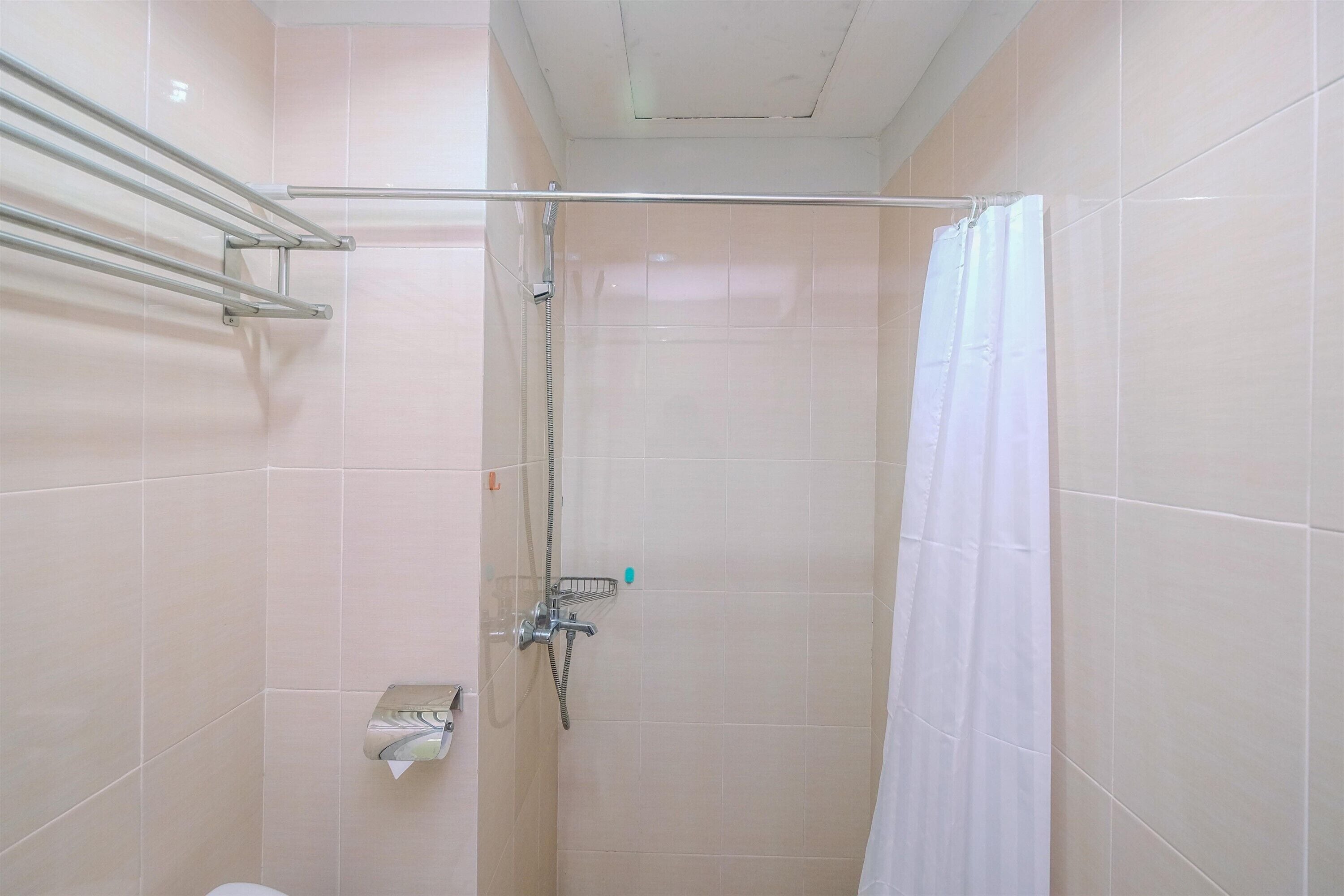 A small, tiled bathroom with a shower, a towel rack, and a toilet.