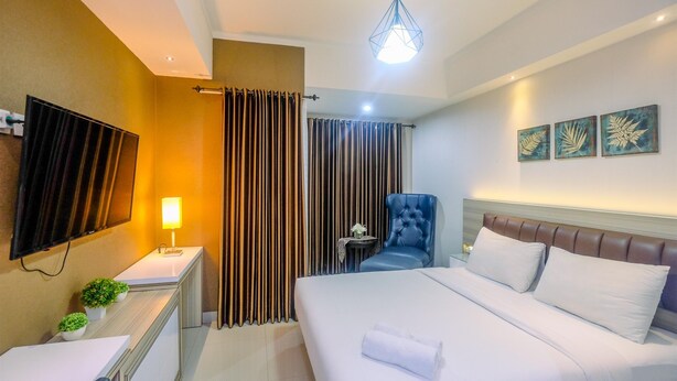 A hotel room with a bed, a desk, a chair, a TV, and curtains.