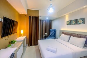 A hotel room with a bed, a desk, a chair, a TV, and curtains. - Fully Furnished With Luxury Design Studio The Oasis Apartment (Cikarang)