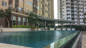 A swimming pool with a covered seating area, surrounded by high-rise residential buildings.