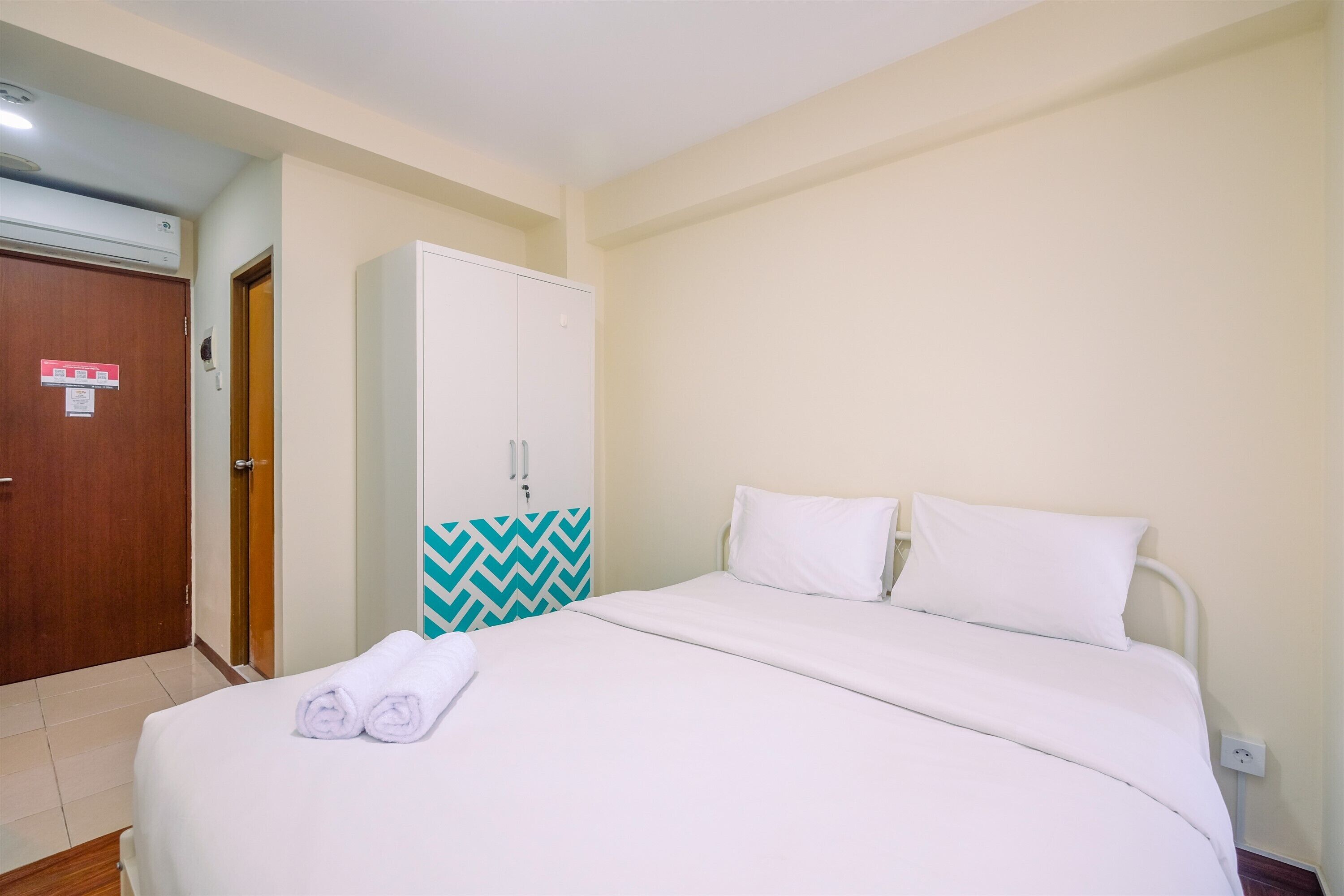 Habitació d'hotel amb un llit, un armari i una porta.