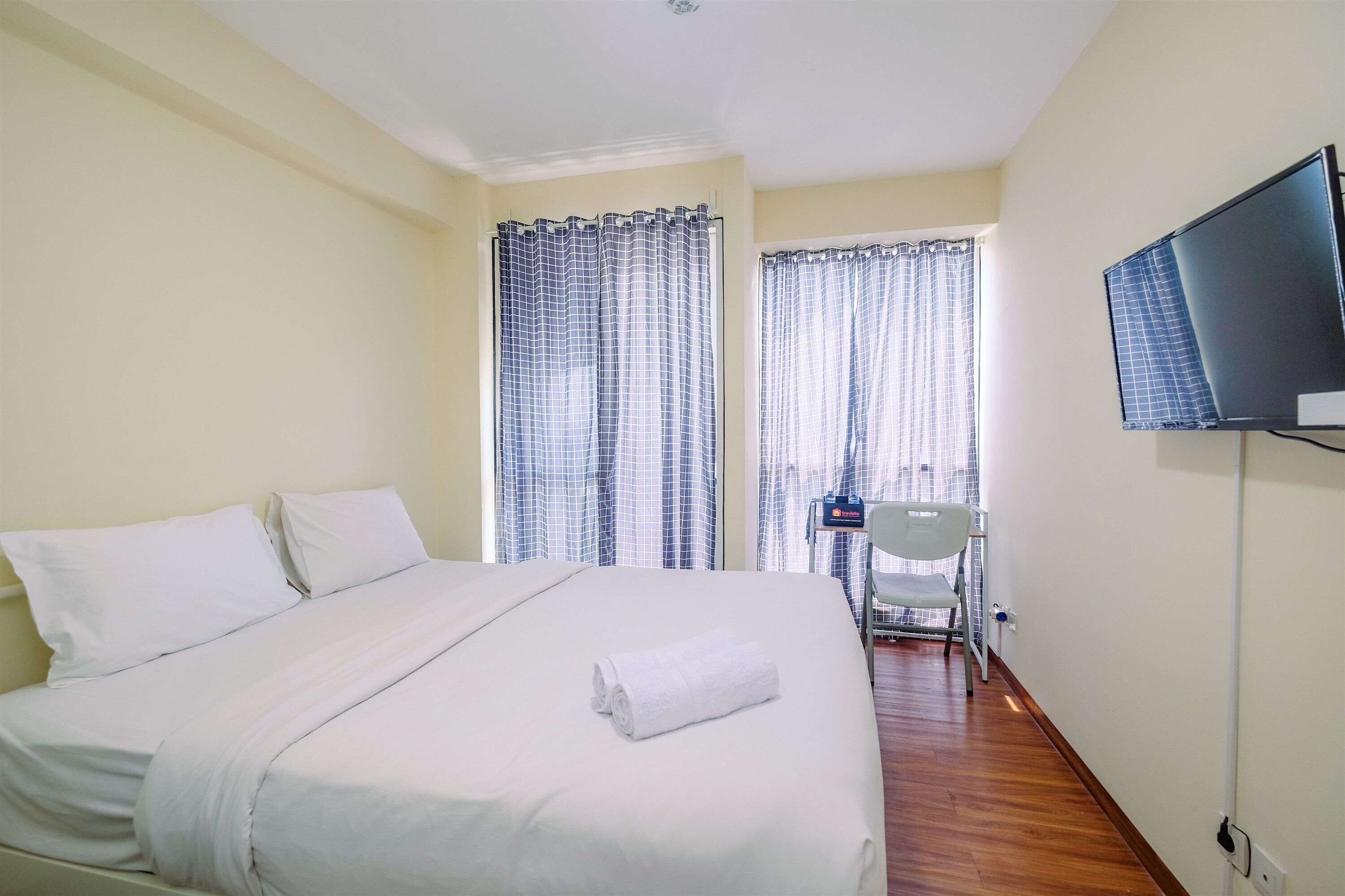 Une chambre d’hôtel avec un lit, une télévision et une chaise.