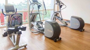 A gym with various exercise equipment, including a stationary bike, elliptical, and treadmills. - Homey And Comfort Studio At Tifolia Apartment (Jakarta)