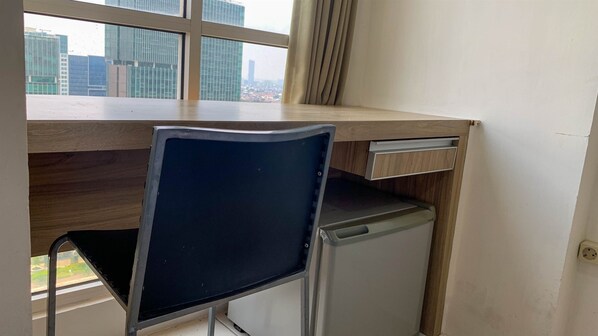 A compact office space with a desk, chair, and a small refrigerator.