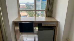 A small, modern room with a wooden desk, a chair, and a refrigerator. - Cozy And Tidy Studio At Tifolia Apartment (Jakarta)