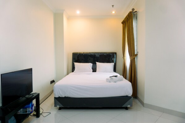 A hotel room with a bed, a TV, and curtains.