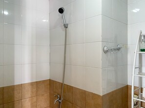 Shower area features a chrome showerhead and hose, surrounded by contrasting tile walls.