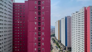 A high-rise building with multiple floors, featuring a prominent red section. - Modern Look And Comfortable 2Br Green Pramuka City Apartment (Jakarta)