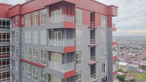 Um edifício com vários andares, varandas e janelas amplas, com vista para o horizonte urbano.