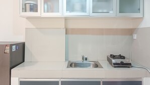 Cozinha com armários brancos, pia de aço inoxidável e aquecedor Rinnai.